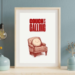 Puede incluir: Una impresión enmarcada en blanco con una ilustración roja de un sofá con una cara sonriente. El texto "COUCH IS CALLING" está en letras rojas sobre el sofá.