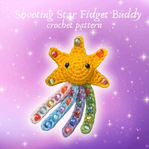 Puede incluir: Un juguete fidget hecho a mano con forma de estrella de ganchillo amarillo con tentáculos con cuentas. La estrella tiene una cara sonriente y los tentáculos son de varios colores, cada uno con cuentas coloridas. El texto de la imagen dice "Shooting Star Fidget Buddy crochet pattern."