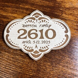 May include: A white wooden sign with a brown ornate border and the text "Dutton Family 2610 April 5-12, 2025".