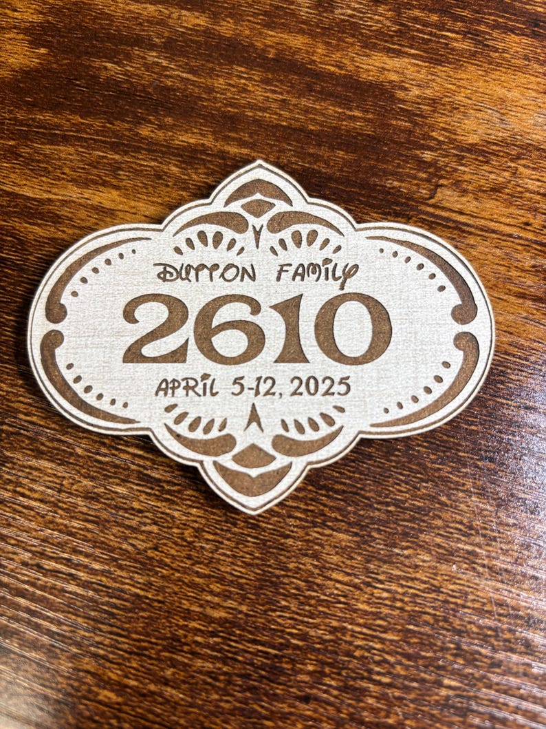 May include: A white wooden sign with a brown ornate border and the text "Dutton Family 2610 April 5-12, 2025".