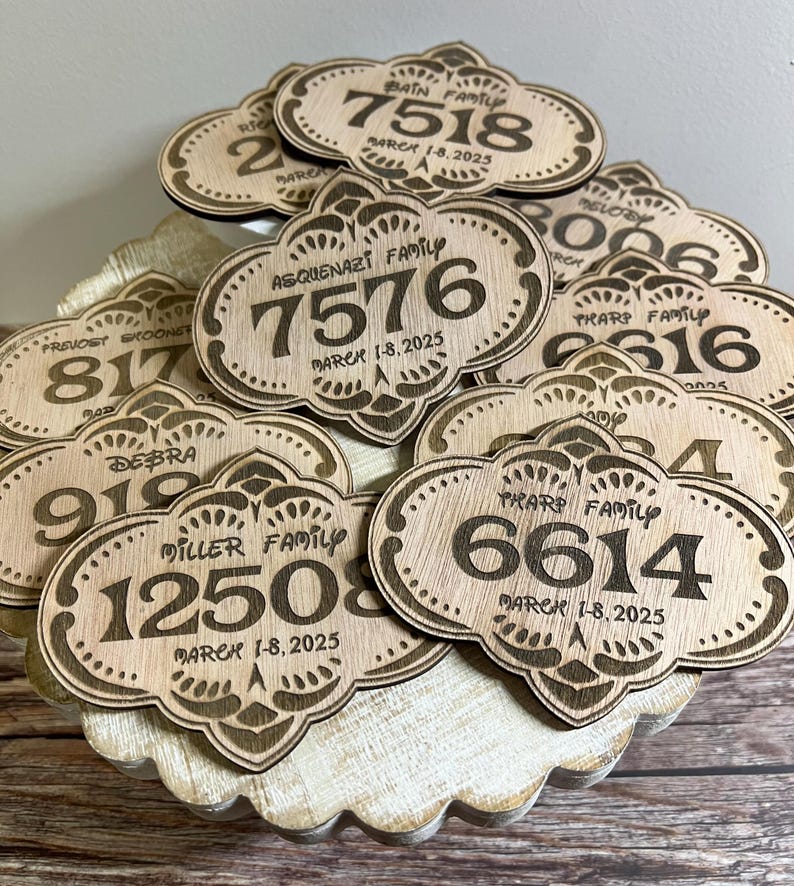 May include: A close-up of a pile of wooden plaques with engraved family names and dates. Each plaque features a unique design with a number and the text "MARCH 1-8, 2025".