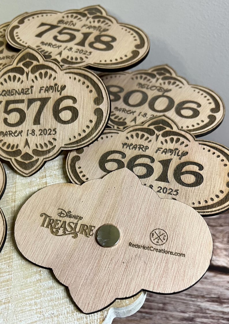 May include: Wooden Disney Treasure magnets with a cloud shape and a magnet on the back. The front of the magnets have a family name, a number, and the year 2025. The back of the magnets have the Disney Treasure logo and the company name "Reds Hot Creations.com".