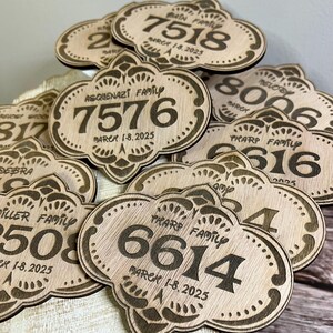 May include: A close-up of several wooden plaques with engraved family names, numbers, and the date "March 1-8, 2025".
