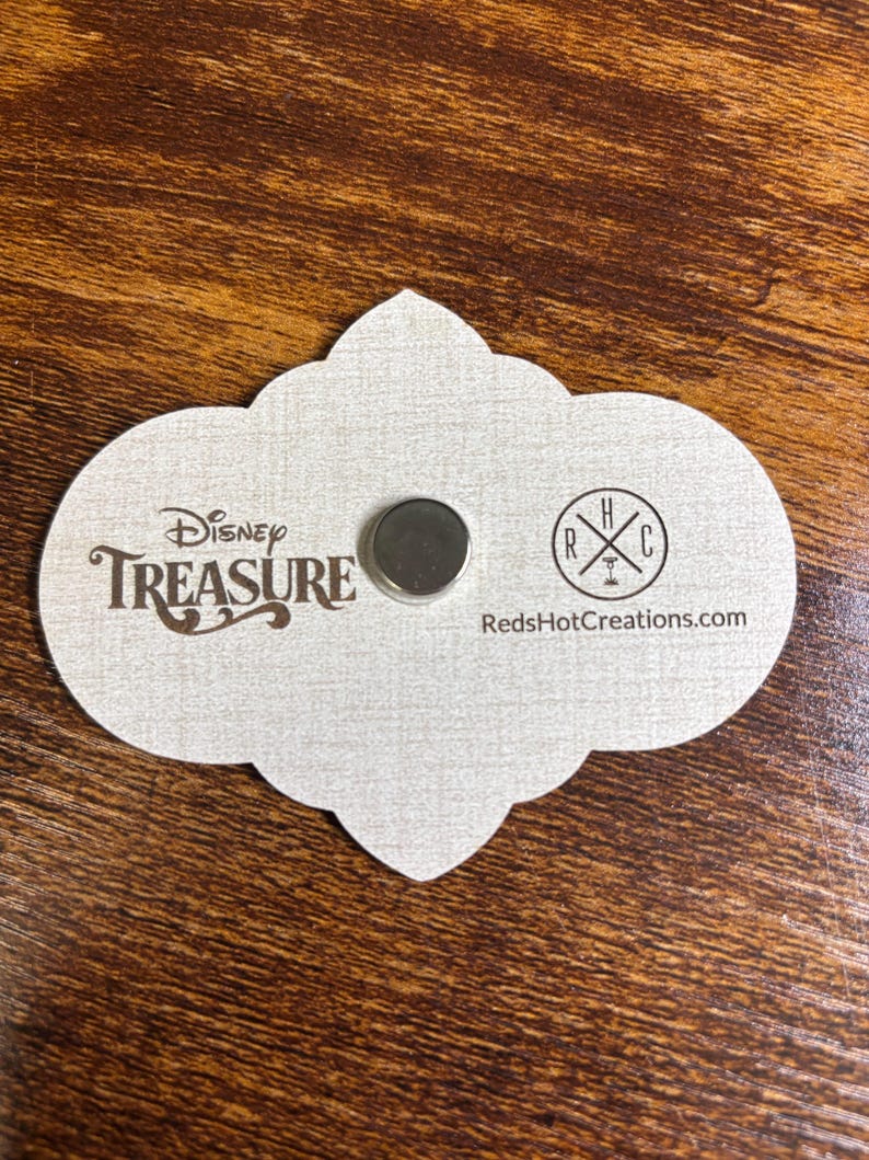 May include: A white card with a cloud-shaped outline. The card has the text "Disney TREASURE" in brown lettering and a small silver magnet. The bottom right corner of the card has the text "RedHotCreations.com" and a logo with the letters "RHC" in a circle.