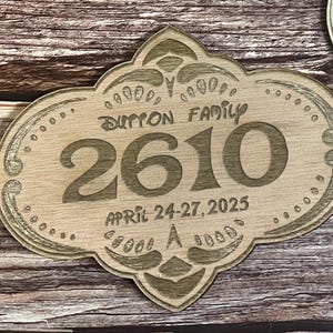 May include: A wooden sign with an ornate design, featuring the text "Dutton Family" and the number "2610". The sign also includes the date "April 24-27, 2025".