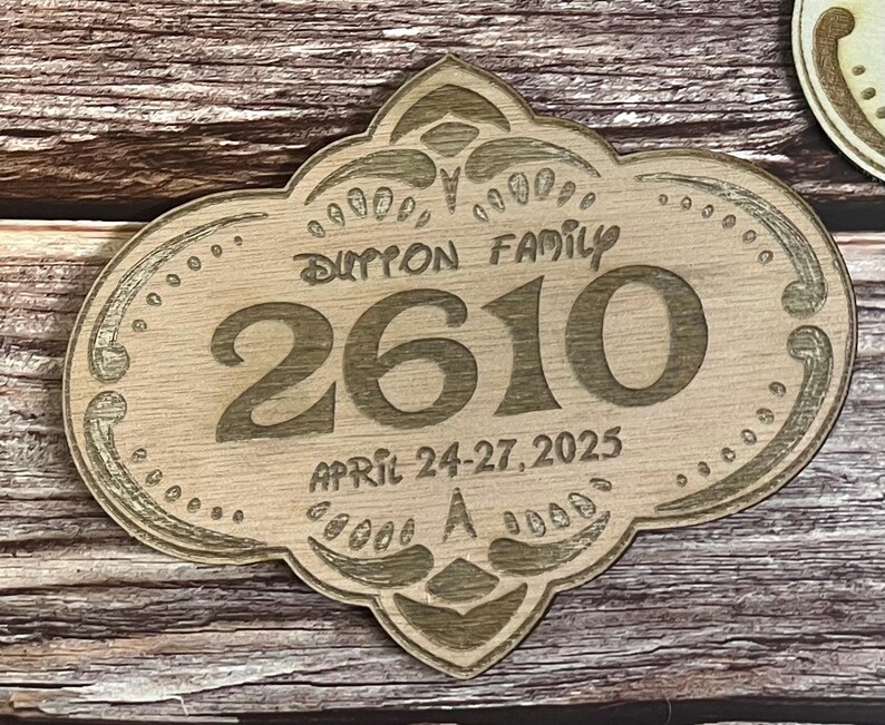 May include: A wooden sign with an ornate design, featuring the text "Dutton Family" and the number "2610". The sign also includes the date "April 24-27, 2025".