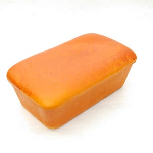 May include: A loaf of bread with a golden-brown crust. The bread is rectangular and appears freshly baked. The color is a warm, inviting orange-brown, suggesting a soft interior.