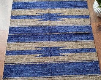 May include: A blue and beige striped rug with a geometric pattern. The rug has fringe on all sides.