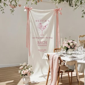 Bachelorette party linen banner with pink ribbons displayed in a soft bridal brunch setting with flowers, table decor, and natural light