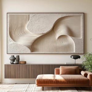 May include: A large rectangular wall art piece featuring a cream-colored textured surface with deep, flowing vertical grooves and smooth, raised sections. The artwork is framed in a thin, dark brown border, creating a high-contrast relief effect.