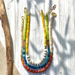 May include: A white ceramic mug with a black handle and the text "But First, Coffee" in a bold, black font. The mug is set against a blurred background, suggesting a cozy setting.