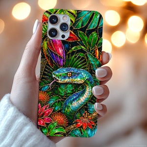 Puede incluir: Una funda para smartphone con una ilustración vibrante y colorida de una serpiente azul y verde enroscada entre un exuberante follaje tropical y flores rojas brillantes. El diseño incluye patrones de hojas detallados sobre un fondo oscuro.