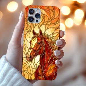 May include: A smartphone case featuring a stained glass style design of a horse head in shades of orange, red, and yellow. The artwork consists of dark outlines forming intricate, flowing patterns that fill the entire surface of the phone cover.