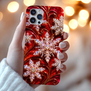 Könnte beinhalten: Eine Smartphone-Hülle mit einem leuchtend roten Hintergrund, geschwungenen goldenen Akzenten und mehreren kristallinen Schneeflocken-Designs. Die Hülle hat eine Aussparung für ein Drei-Linsen-Kamerasystem in der oberen linken Ecke.