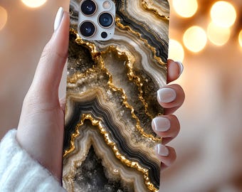 Puede incluir: Una funda para smartphone con un patrón detallado de piedra ágata con capas de colores negro, blanco y beige. El diseño incluye vetas de oro metálico que recorren el centro, imitando formaciones de geodas naturales y cristales.