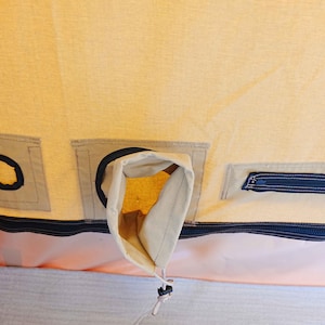 May include: A beige canvas tent with a black zipper and a black fabric flap with a hole in the center. There is a small black zippered pocket on the right side of the image.