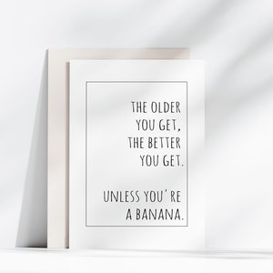 Op de afbeelding: Een witgelijste print met de tekst "THE OLDER YOU GET, THE BETTER YOU GET. UNLESS YOU'RE A BANANA." De print leunt tegen een neutrale achtergrond.
