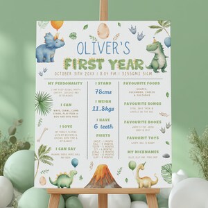 May include: A rectangular milestone sign titled Oliver's First Year featuring watercolour dinosaur illustrations, a volcano, and palm leaves. The board displays personal statistics including 78cms, 11.8kgs, and 6 teeth, alongside categories for favourite foods, songs, books, toys, and nicknames.