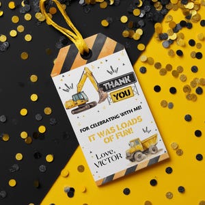 May include: A construction-themed thank you tag with a yellow string. The tag features a yellow excavator and dump truck illustration, with the text "THANK YOU" and "IT WAS LOADS OF FUN!" on a white background, with black and yellow confetti.