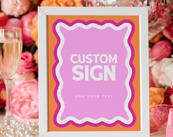 May include: A white rectangular frame containing a sign with an orange background and a pink wavy-edged center. The sign features the white text CUSTOM SIGN in large letters and the smaller text ADD YOUR TEXT centered below in white.
