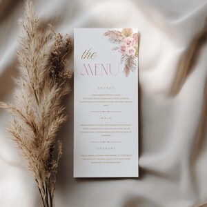 May include: A vertical menu card featuring the text "the MENU" in gold and pink, decorated with a floral illustration of pink roses and dried pampas grass. The menu lists sections for Entrée, Main, and Dessert with detailed food descriptions.