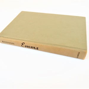 May include: A hardcover book titled "Emma" with a light green cover and a tan spine. The author's name, Kenyon, is printed on the spine, along with the title "Emma" in black lettering. The book is set against a white background.