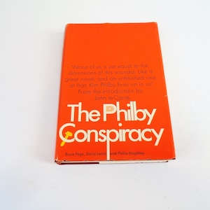 May include: An orange book cover with the title "The Philby Conspiracy" in white text. The book is by Bruce Page, David Leitch, and Phillip Knightley. The cover also includes a quote from John le Carre.