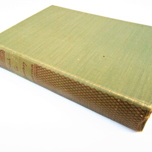 May include: A vintage book with a faded green cover. The spine features ornate red and gold detailing and text. The book's edges show signs of wear, suggesting its age and use. The book is set against a white background.