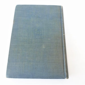 May include: A blue hardcover book with a textured cover. The book has a small, square design on the front cover.