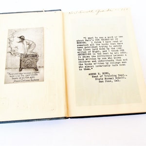 May include: An open book with a black and white illustration of a person standing on a box. The book is titled "Our Ancestors in Europe" and includes a quote from Agnes E. Howe, Head of Training Dept., State Normal School, San Jose, Cal.