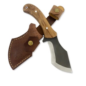 Könnte beinhalten: Ein Jagdmesser mit gebogener Klinge und Holzgriff, gepaart mit einer braunen Lederscheide. Das Messer hat eine dunkle Klinge und einen hellen Holzgriff, der mit einem Lederriemen befestigt ist.