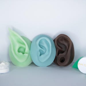 May include: Four different colored silicone ear molds, a makeup brush, a container of powder, and a small container with the word "piccolo" on it.