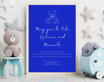 May include: A framed print with a blue background and white text that reads "May you be like Ephraim and Menashe." A small teddy bear illustration is at the top. Additional text is below. The frame is beige.