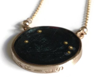May include: A gold chain necklace with a round pendant featuring the Aries constellation in gold glitter on a black background. The pendant is inscribed with the word "Aries".