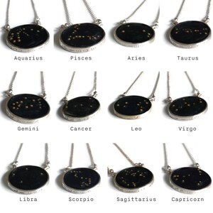 May include: Twelve silver necklaces with black circular pendants featuring gold star constellations representing the twelve zodiac signs: Aquarius, Pisces, Aries, Taurus, Gemini, Cancer, Leo, Virgo, Libra, Scorpio, Sagittarius, and Capricorn.