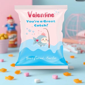 May include: A pink and blue Valentine's Day treat bag with the words "Valentine" and "You're a Great Catch!" The bag features a cartoon fish with a fishing rod. The bottom of the bag says "Your friend, Amelia".