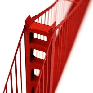 Closeup of the upper part of the Golden Gate bridge model features suspension cables and one of the towers. The 3d scale model is made out of red die-cut cardstock parts.
