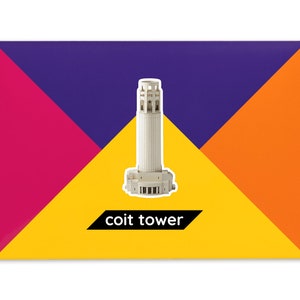 Product packaging for the Coit Tower paper model kit. A recangular bright coloured cardstock envelope features four large triangles in yellow, magenta, purple and orange with an image of a finished model at the centre and the product title below.