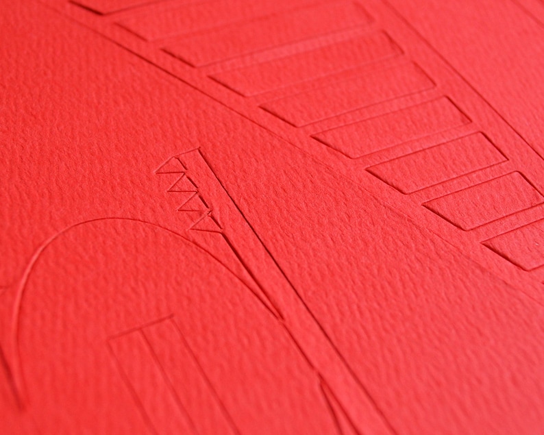 Closeup of a bright red die-cut cardstock sheet with parts to be easily removed for building Golden Gate bridge scale model out of PaperLandmarks paper model kit.