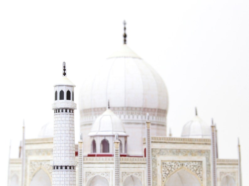 Closeup the 3D paper model of Taj Mahal shows one of its minarets with the central dome and kiosk domes in the background.