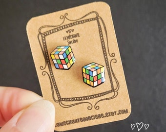 May include: A pair of colorful Rubik's Cube stud earrings on a brown card with the text "La Méchante Sorcière" and the website address "lamechanteesorciere.etsy.com".
