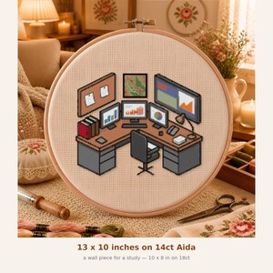 May include: A cross-stitch embroidery in a wooden hoop featuring an isometric office desk setup with three computer monitors displaying charts, a chair, and a corkboard. The text below states 13 x 10 inches on 14ct Aida and 10 x 8 in on 18ct.