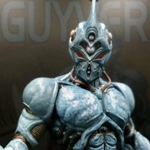 Puede incluir: Figura de acción azul claro detallada de un guerrero alienígena humanoide. La figura tiene un casco con un cuerno central, ojos rojos y detalles intrincados en la armadura. La figura es musculosa y tiene un torso y extremidades detallados.