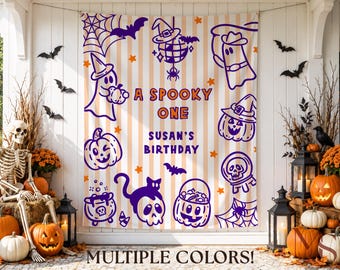 May include: A rectangular fabric backdrop featuring vertical beige and white stripes with purple and orange Halloween-themed illustrations including ghosts, pumpkins, bats, a disco ball, and a spider web. The text reads A SPOOKY ONE SUSAN'S BIRTHDAY.