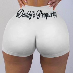May include: White athletic shorts with the text "Daddy's Property" printed on the back.
