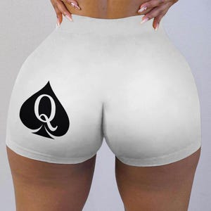 May include: White athletic shorts with a black spade and the letter Q printed on the left leg.