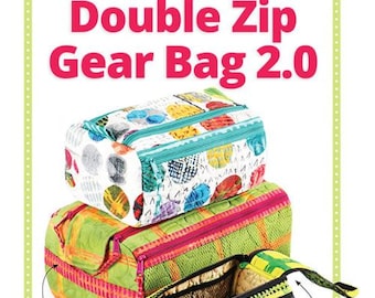 May include: A set of three colorful zippered bags with a double-zip flap for easy access. The bags are made of quilted fabric and have a sturdy carrying handle. The largest bag is green with yellow and pink accents. The middle bag is pink with green and yellow accents. The smallest bag is white with green, yellow, and red accents. The bags are stacked on top of each other. The text "Double Zip Gear Bag 2.0" is at the top of the image. The text "Includes coupon for $5 Add-On Video Tutorial" is in a blue circle in the lower left corner of the image. The text "Double-zip flap opens wide for easy access" is in the lower right corner of the image. The text "Spacious main compartment, Two exterior zippered pockets, Two interior slip pockets, Three functional sizes" is listed below the text "Double-zip flap opens wide for easy access".