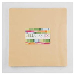 May include: A stack of beige fabric squares with a colorful label that reads "BELLA SOLIDS moda". The label features a rectangular design with various colors including green, pink, and orange. The fabric appears to be for quilting or crafting.