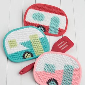 May include: Three colorful hot pads shaped like vintage campers. The hot pads are red, blue, and pink with white accents. The text "SNACK SHACK HOT PADS" is at the bottom of the image. The text "ATK-180" is in the bottom right corner.