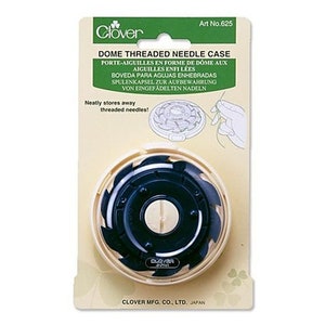 May include: A white plastic dome-shaped needle case with a black center and a serrated edge. The case is labeled "Dome Threaded Needle Case" and "Clover" in green lettering. The text "Art No. 625" is printed in black lettering.